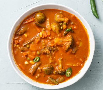 Vertical shot of vegetable curry with cauliflower, beans, corn, spicy pepper and lime